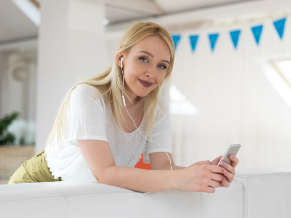 Pretty girl using her smartphone on couch at home in the living room
