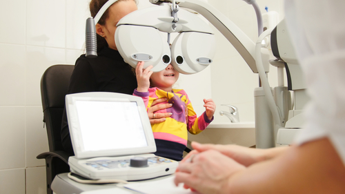 High technology in ophthalmology - optometrist in clinic checking little girl's vision - children's medicine, horizontal